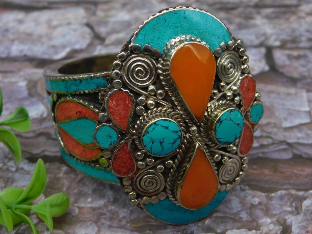 METAL CUFF BRACELET WITH TURQUOISE AND RED CORAL: Beautifully designed cuff bracelet featuring turquoise, coral, and orange stone inlays. The intricate metalwork includes spiral and textured accents, giving the piece a detailed and refined finish. Th