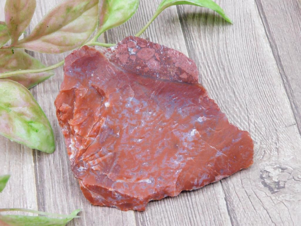 Raw Red Rock Specimen for Collectors or Study: A raw red rock specimen, ideal for collectors or geological study. The rock presents a natural rough surface with visible color variations and texture, making it unique. Item includes a size reference