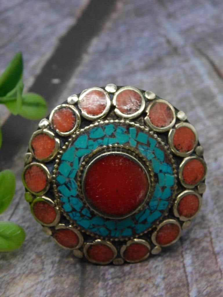 Turquoise and Red Coral Adjustable Ring Rock Stone Lapidary Specimen: Round decorative ring featuring a central red inlay surrounded by turquoise and red insets, accented with metallic detailing. Coin shown for scale; weight details are unspecified but item is lightweig