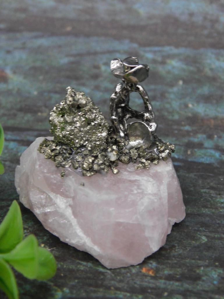 Rose Quartz Base with Pyrite and Metal Figurine ROCK STONE LAPIDARY SPECIMEN: Ornamental display featuring a rose quartz base with pyrite mineral accents. A metallic figurine is situated atop the piece, providing a distinctive focal point. Measuring tool present for scale refer