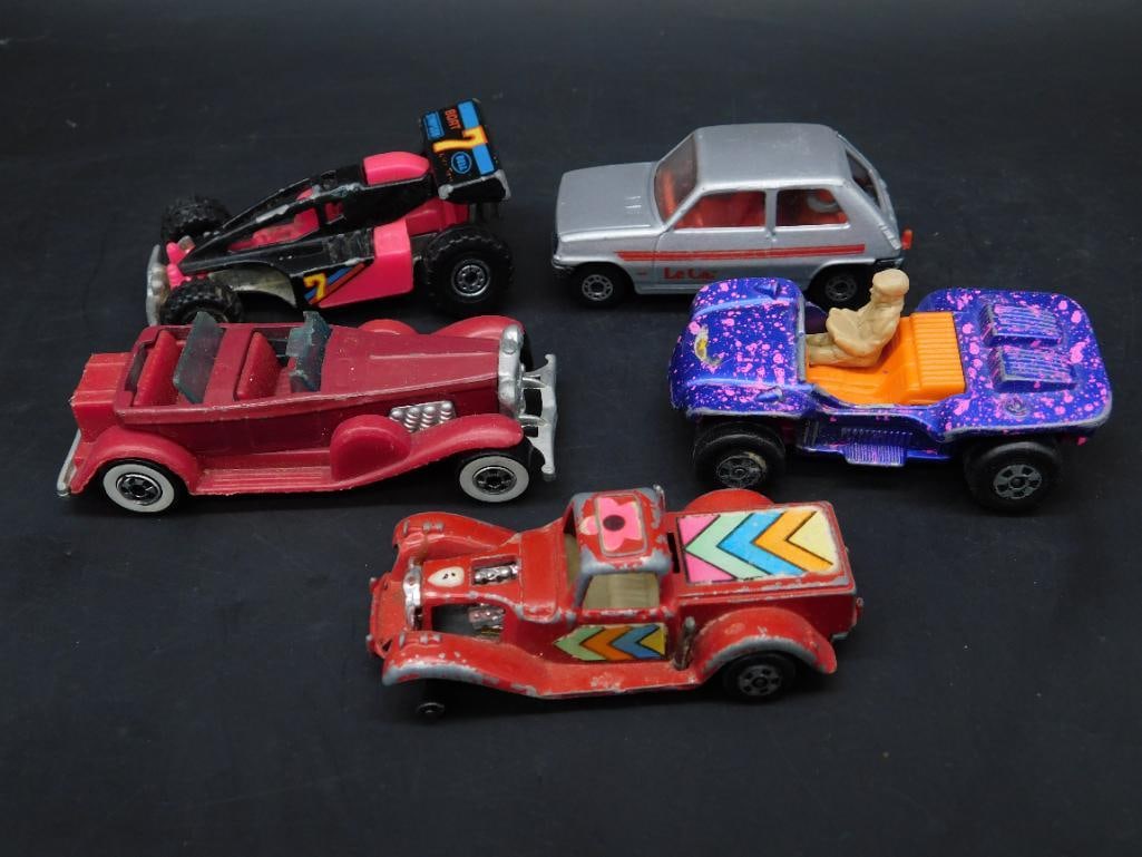 Set of 5 Die-Cast Cars from Various Brands: This lot includes five die-cast vehicles featuring various designs, colors, and manufacturers. Notable brands include Hot Wheels and Matchbox, as indicated on some undersides. Models vary, including v