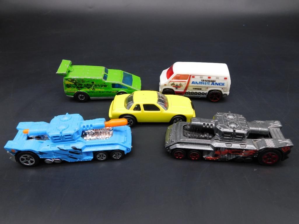 Lot of 5 Assorted Die-Cast Hot Wheels Cars: This lot features 5 die-cast Hot Wheels vehicles, including a green 'Spoiler Sport,' a white ambulance van, a yellow sedan, a blue 'Invader' tank-style vehicle, and a black tank-style vehicle. All ite