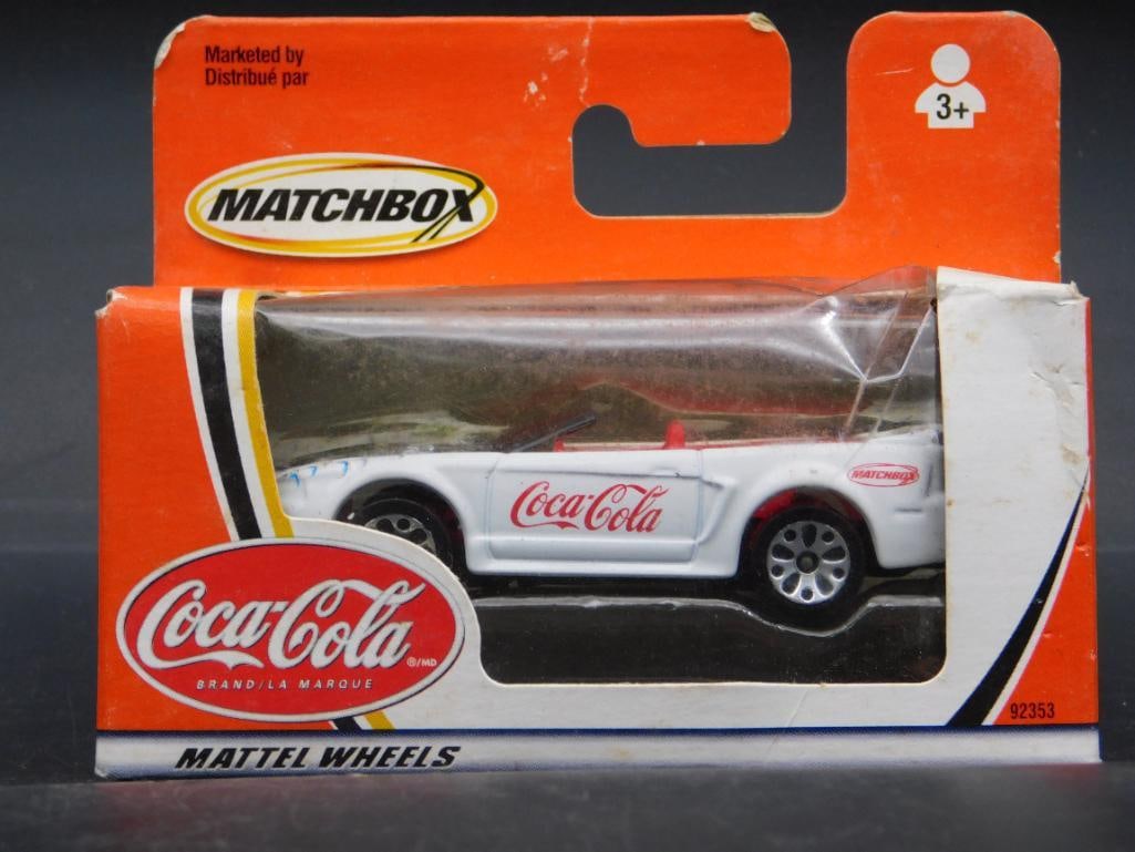 Matchbox Mattel Coca-Cola Branded Diecast Car in Box: Matchbox Mattel diecast car with Coca-Cola branding. Comes in original, unopened packaging. Packaging includes markings for collector information and logos, suitable for ages 3. Depicts a white sports