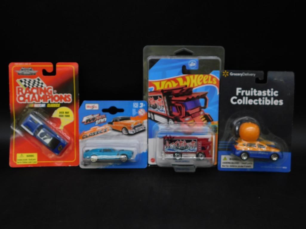 Lot of Four Collectible Diecast Model Cars: A set of four collectible diecast model cars from various brands: Racing Champions, Fruittastic Collectibles, Hot Wheels, and Maisto. Each item is in its original unopened packaging, showcasing a vari