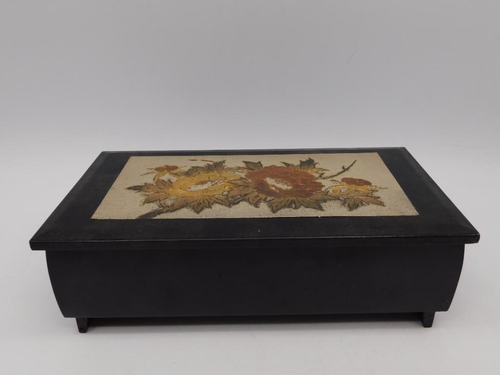 Black Wooden Music Box with Floral Inlay and Red Interior: - Black lacquered wooden exterior with an inlaid floral design featuring shades of yellow, orange, and green. | - Interior lined with red fabric and includes compartments suitable for jewelry or small