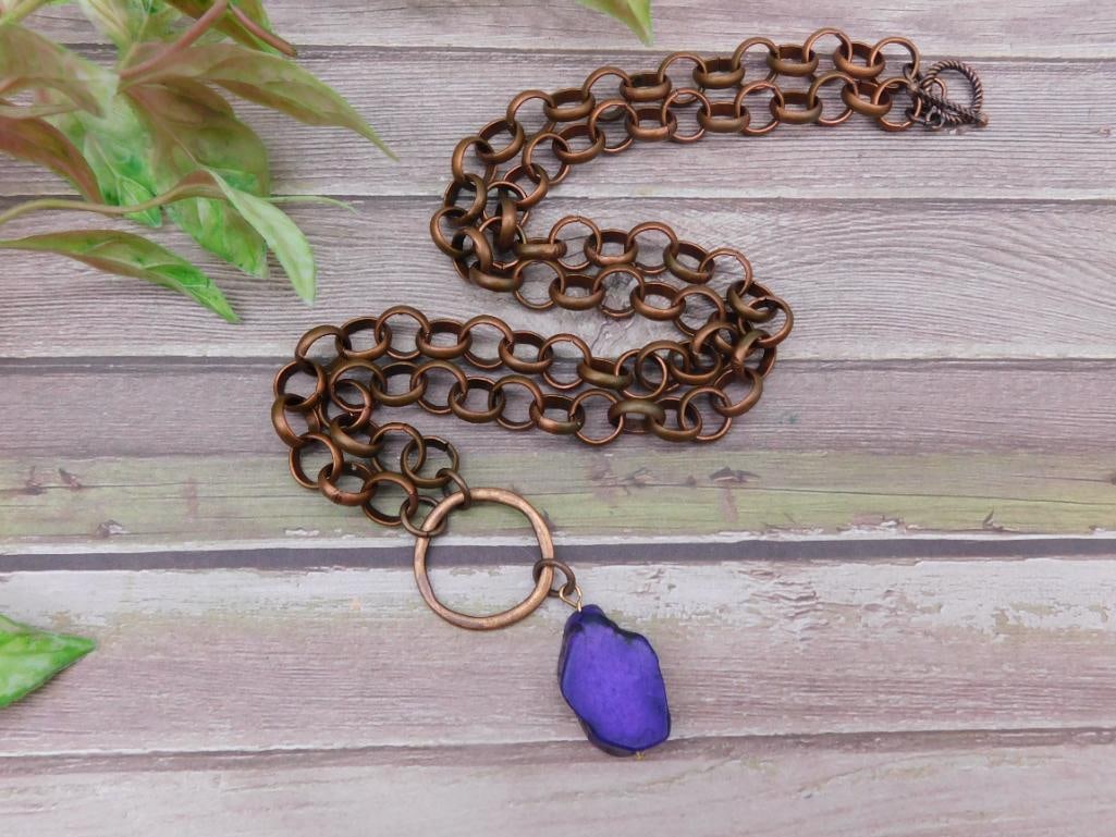 Copper Chain Necklace With Purple Stone Pendant: Double-strand copper necklace featuring circular chain links and a purple stone pendant. Includes a toggle clasp for secure closure. Ideal for those seeking a bold and colorful accessory.