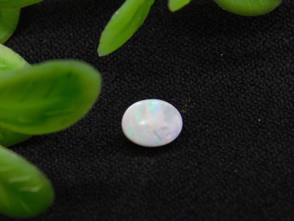 RAINBOW MOONSTONE CABOCHON ROCK STONE LAPIDARY SPECIMEN: - Round opal gemstone with a smooth finish. | - Reflects light with a multicolored play-of-color effect. | - Compact size, as shown relative to a U.S. quarter coin for scale. | - Suitable for jewelry 