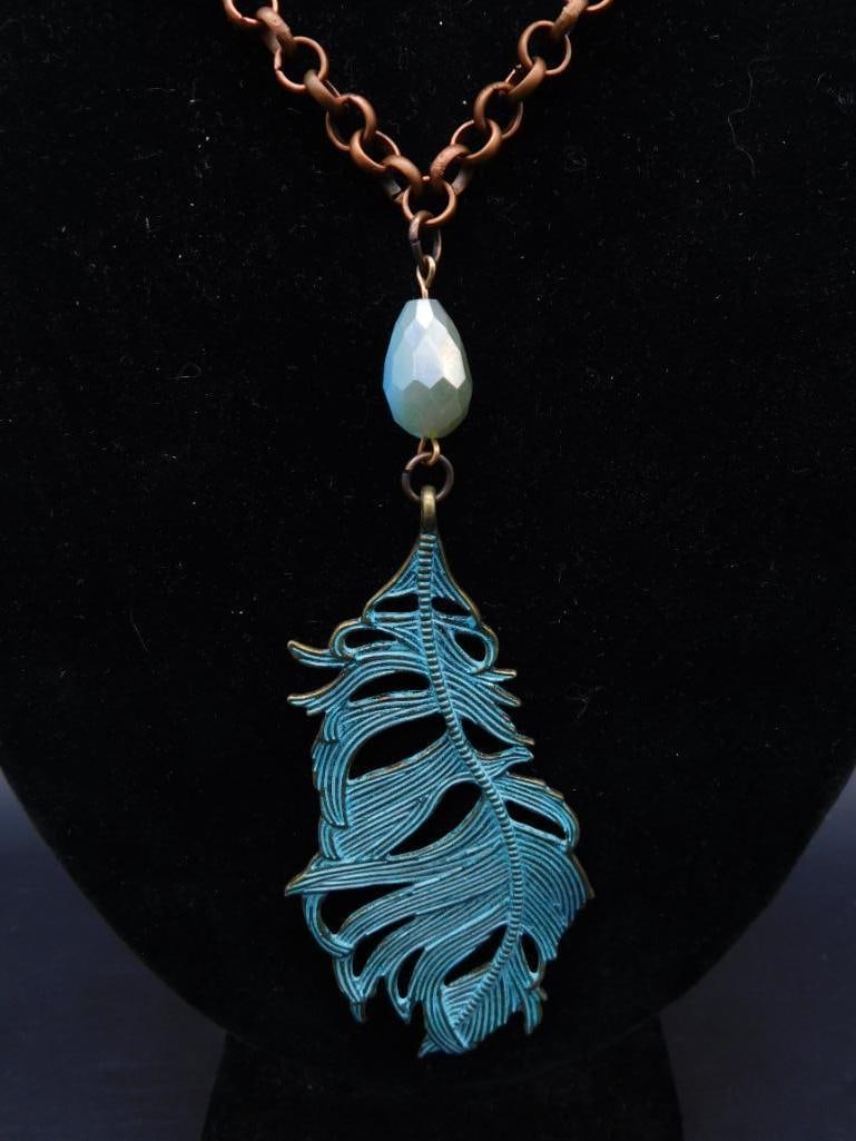 Gold-Tone Chain Necklace With Blue Feather Pendant: Gold-tone chain necklace featuring a vibrant blue feather-shaped pendant. Pendant includes an additional teardrop-shaped accent in a complementary light blue color. Chain consists of interconnected ri