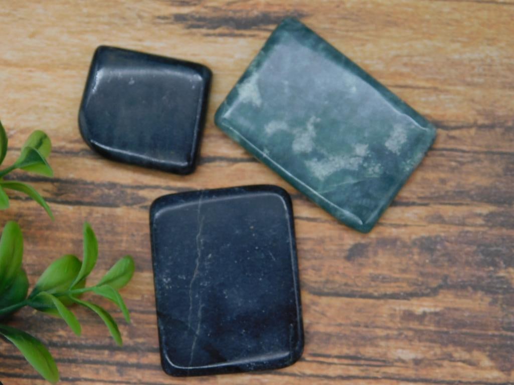 NEPHRITE JADE ROCK STONE LAPIDARY SPECIMEN: This lot includes three polished stone specimens with a total combined weight of 58 grams. The stones vary in color and design, with two darker stones and one in a greenish shade. A quarter is shown f