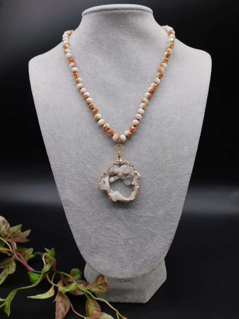 Beaded Necklace With Geode Pendant and Gold Detailing: This necklace features a string of round multicolor beads and includes a unique geode pendant. The geode pendant has gold-colored edging and an open-center design that highlights its natural crystal f
