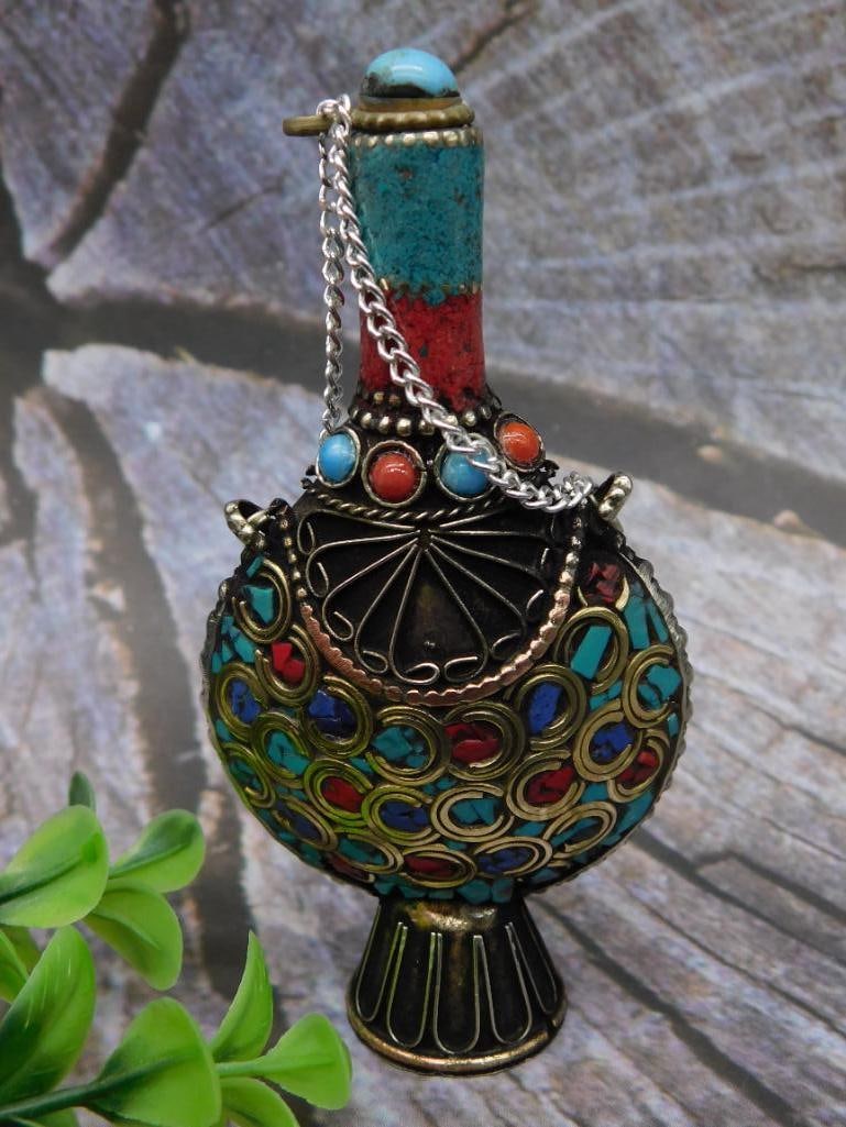 Multicolor Decorative Brass Vessel with Chain: Unique brass vessel adorned with colorful stones and enamel detailing. Features a removable stopper and a chain attachment for easy handling. The vessel showcases an ornate peacock-like design with vi