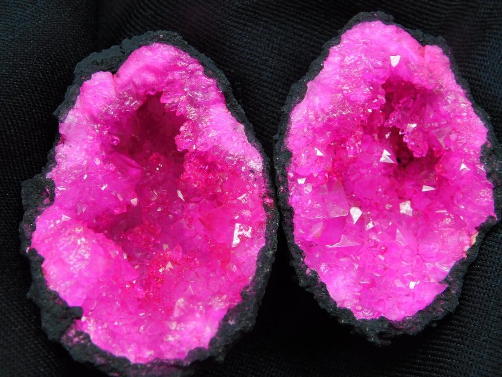 Bright Pink Quartz Geode Rock Stone Lapidary Specimen: - Pair of vibrant pink geode crystals with a natural quartz interior. | - Features a striking druse of crystals in both halves. | - Black exterior with vivid, shimmering pink inner crystals. | - Item