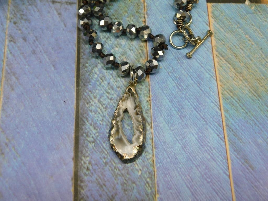 Geode Slice Pendant on Sparkle Bead Necklace: - Features a teardrop-shaped druzy pendant with a natural raw edge in a metallic silver-tone setting. | - Includes a double-layer beaded chain with faceted black and silver-toned beads. | - Secured wi