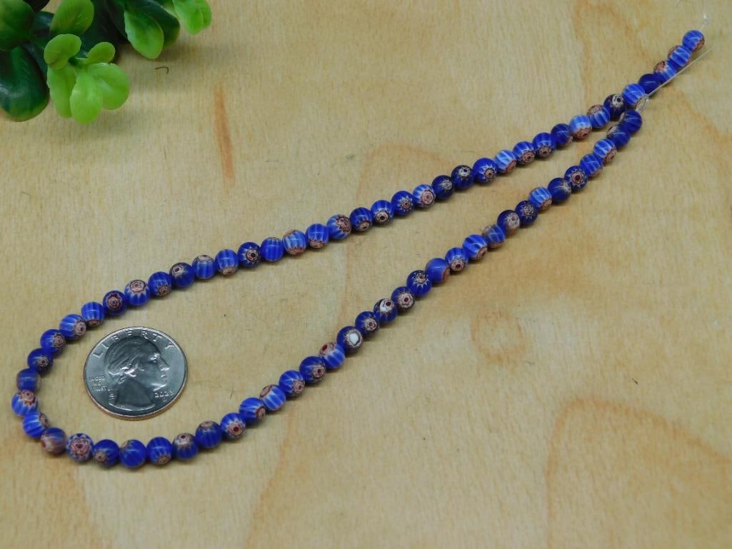 African Trade Beads Rock Stone Lapidary Specimen: - Features a strand of blue Millefiori glass beads with intricate floral patterns. | - Beads are spherical and display vibrant blue hues interspersed with colorful floral designs. | - Approximate bead