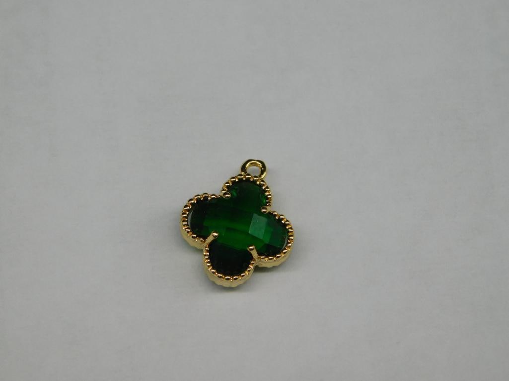 Gold-Toned Green Clover-Shaped Pendant: - Clover-shaped pendant featuring a green center stone. | - Gold-toned edges with textured detailing. | - Includes a small circular bail for attachment to a chain or jewelry. | - Compact size; shown n