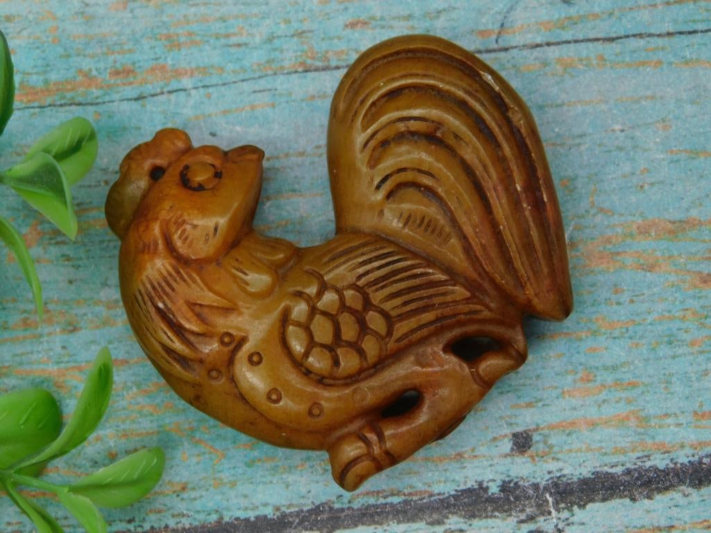 Hand-Carved Brown Jade Rooster Figurine, 39g: A hand-carved brown stone rooster figurine weighing 39 grams. Features intricate feather detailing and a carved tail. Compact size, shown next to a U.S. quarter for scale. Listed for the 2024 Antique
