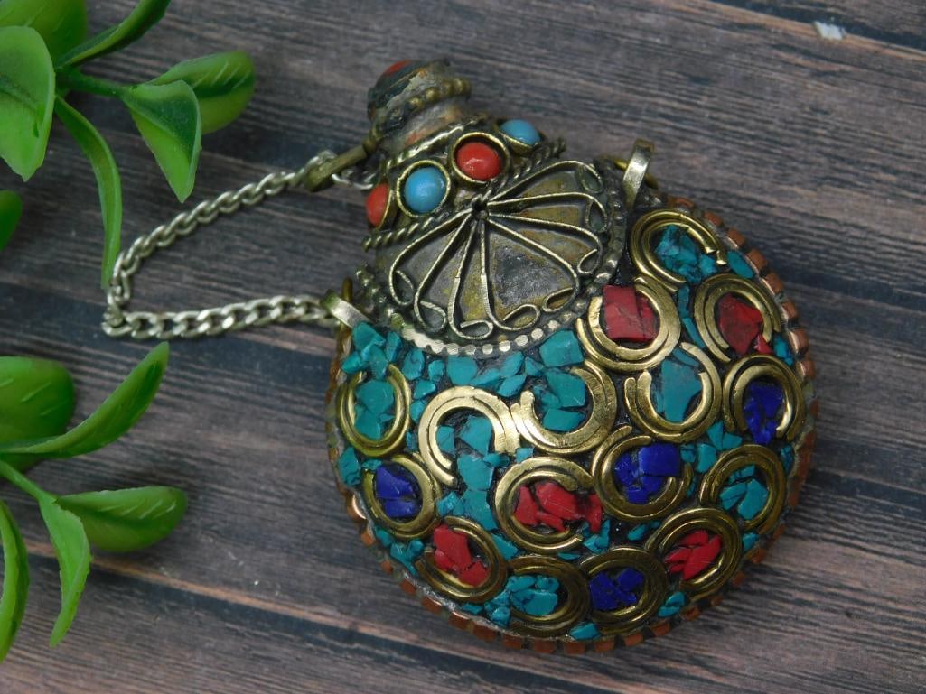 Colorful Ornamental Metal Snuff Bottle With Chain: Circular ornamental metal flask featuring vibrant inlays of red, blue, turquoise, and green stones or enamel. Decorated with intricate metalwork, including crescent-shaped accents and an embossed desi