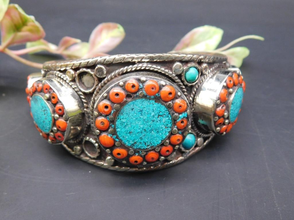 Cuff Bracelet With Turquoise and Coral Accents: Cuff bracelet featuring detailed three medallion designs adorned with turquoise and red coral accents. The outer edge includes intricate metalwork. Bracelet measures approximately 2 inches tall, as sh