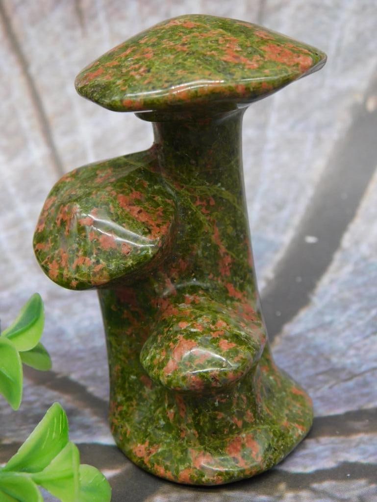Polished Stone Sculpture With Mushroom-Like Design: This is a polished stone sculpture made from a mottled green and reddish-brown material. The sculpture features a unique shape with overhanging sections that resemble mushroom caps. The weight is note