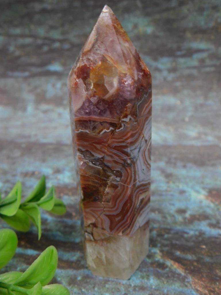 Polished Agate Crystal Point with Banded Patterns: Polished agate crystal point showcasing intricate banding patterns with a mix of red-orange, white, and earthy tones. Features a pointed tip and multi-faceted surfaces. Weighs 83 grams and is ideal fo