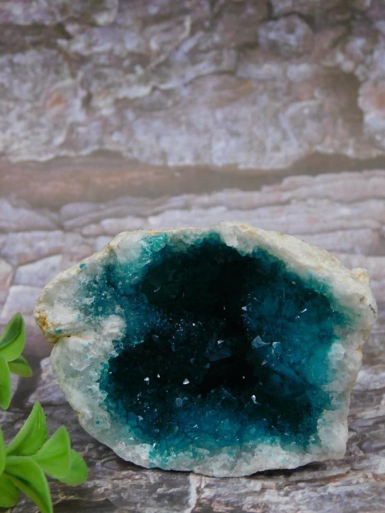 Blue Quartz Geode Specimen: Natural blue quartz geode featuring crystalline structures within a stone casing. The geode displays a vibrant blue center with sparkling crystal textures, complemented by white edges around the openi