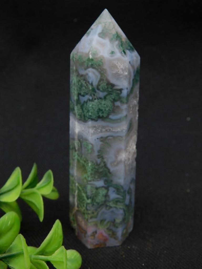 Polished Green and White Moss Agate Crystal Point: This polished Moss Agate crystal features a blend of green and white patterns with a pointed design. It is in excellent condition, suitable for display or collection. The piece has a natural stone com