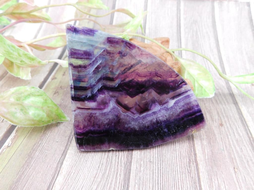 Purple Fluorite Rock Stone Lapidary Specimen: A unique slice of purple fluorite featuring a natural zigzag banding pattern. This piece emphasizes gradient hues of deep purple, with translucent qualities. Measures approximately 4 inches at its lon