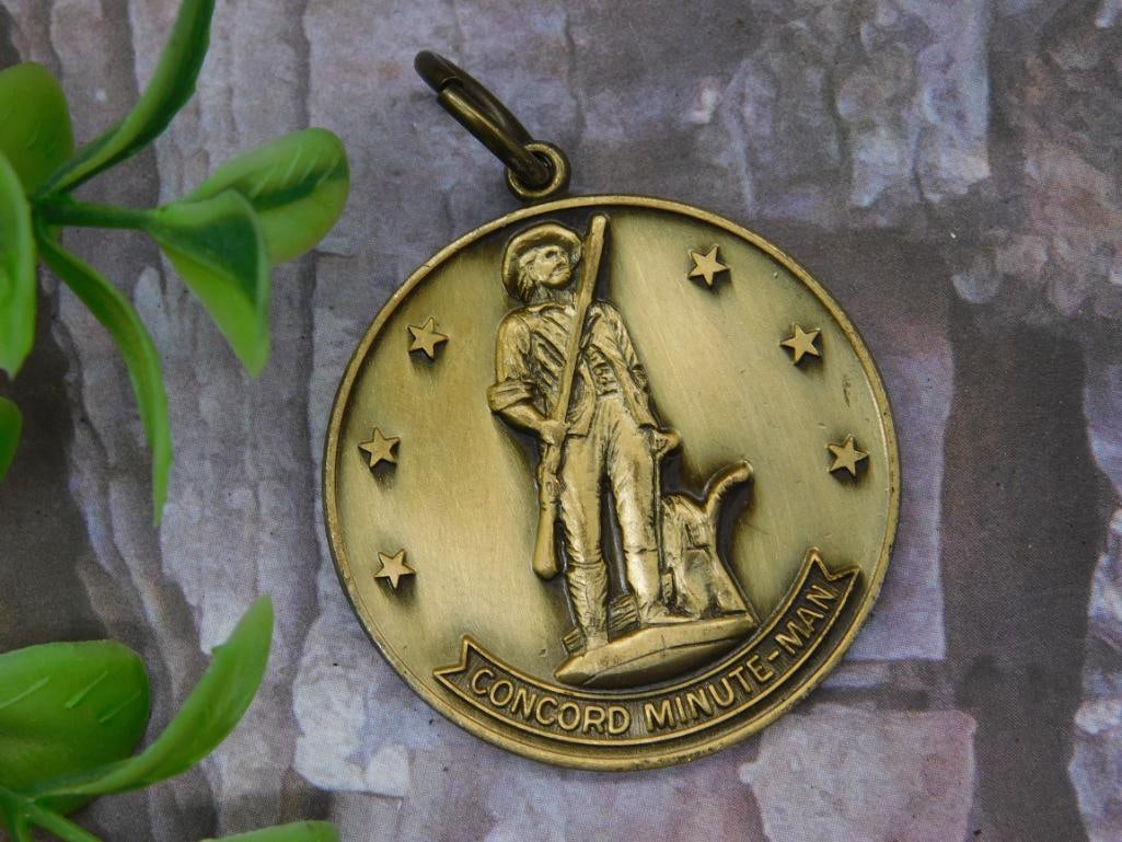 Concord Minute-Man Commemorative Medal Pendant: Bronze-tone medal pendant featuring the Concord Minute-Man design. Front depicts a soldier with musket surrounded by five stars and the text "Concord Minute-Man." The reverse displays "United States o