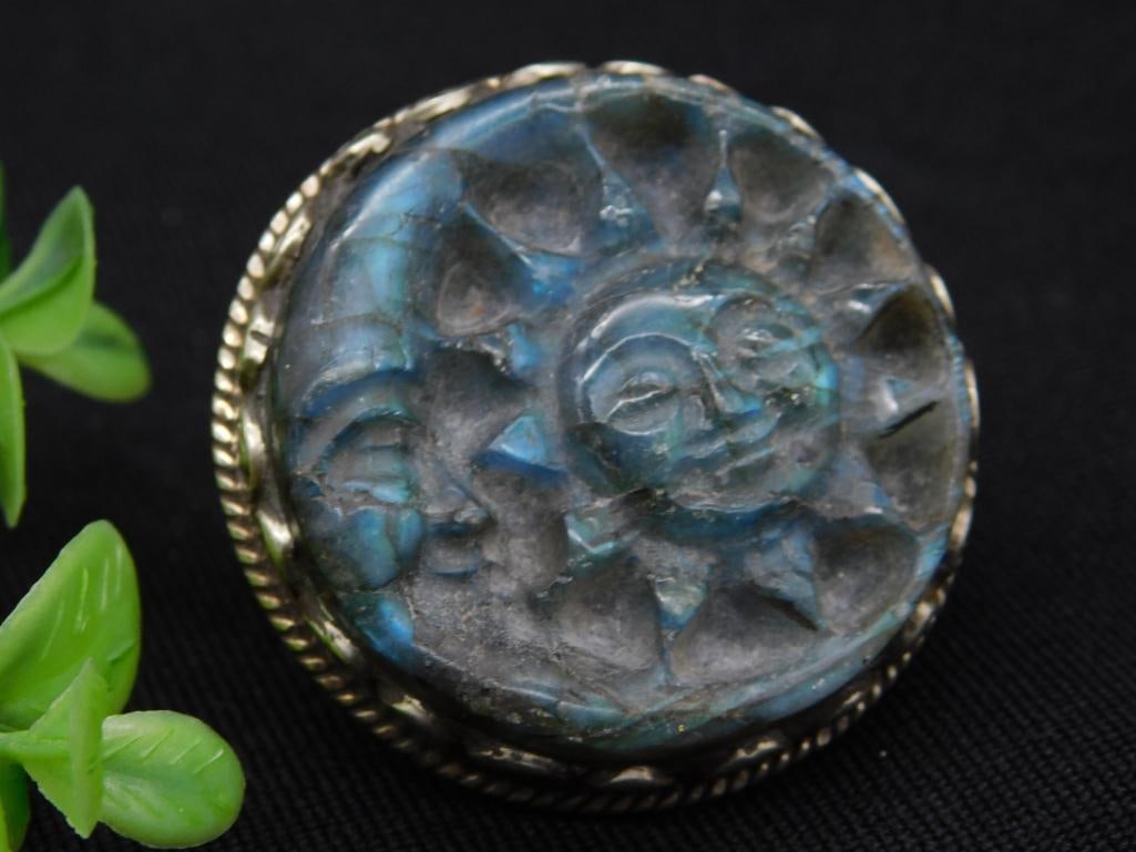 Carved Labradorite and Silver-Tone Brooch with Sun Design: Round brooch featuring a carved stone with a sun motif and metallic detailing. Rear surface includes ornate scrollwork and an integrated pin for secure attachment. The piece appears to be constructed