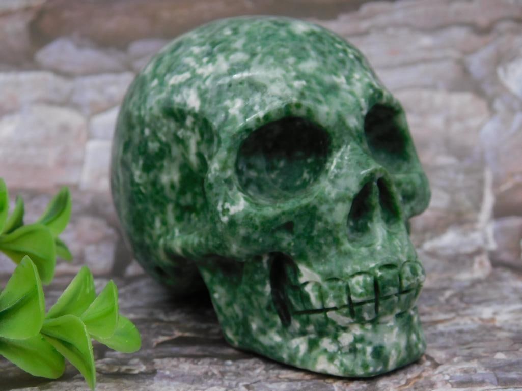 TREE AGATE SKULL ROCK STONE LAPIDARY SPECIMEN: This is a green stone skull sculpture featuring a polished surface with natural marbling effects. The piece appears to be carved from a single stone and is designed with detailed facial features. A me
