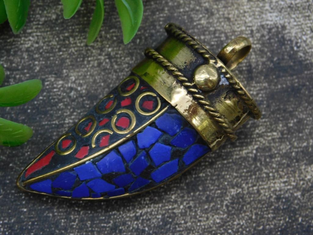 Lapis Lazuli and Red Coral Horn Pendant: - Unique brass pendant featuring vibrant red and blue mosaic inlay. | - Intricate circular motifs on the body of the mosaic design. | - Approximate size relative to a U.S. quarter for perspective. | -