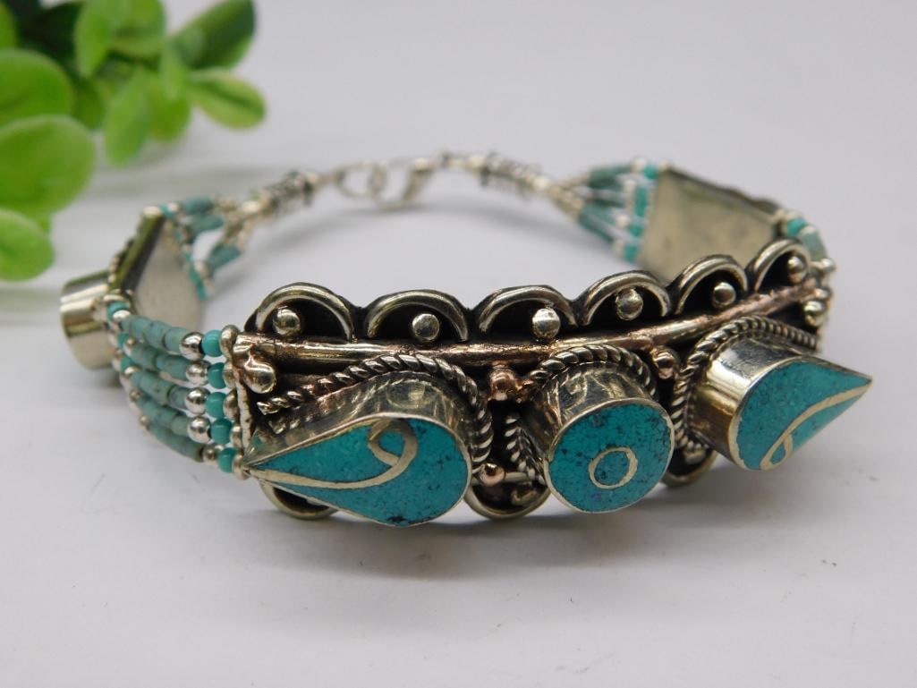 Turquoise-Inspired Bracelet with Ornate Detailing: - Silver-tone bracelet adorned with turquoise-inspired accents. | - Features detailed decorative elements including a central ornamentation. | - Multi-strand band consisting of smaller, beaded accents