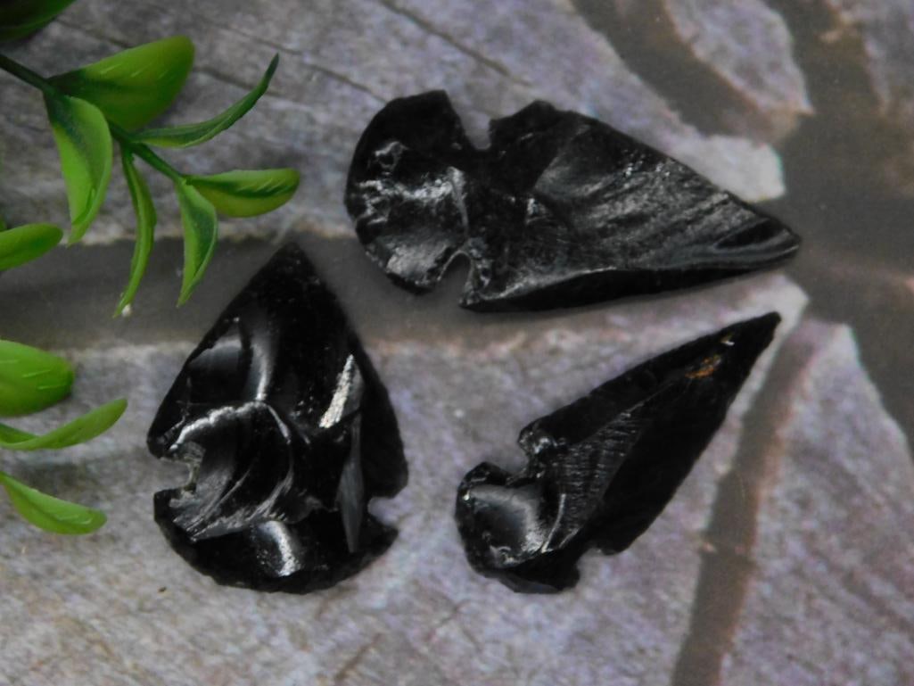 Three Obsidian Arrowheads Rock Stone Lapidary Specimen: - Lot includes three obsidian arrowheads showcasing sharp edges and detailed craftsmanship. | - Material: Obsidian, known for its natural black glass-like appearance. | - Each item displays unique fla