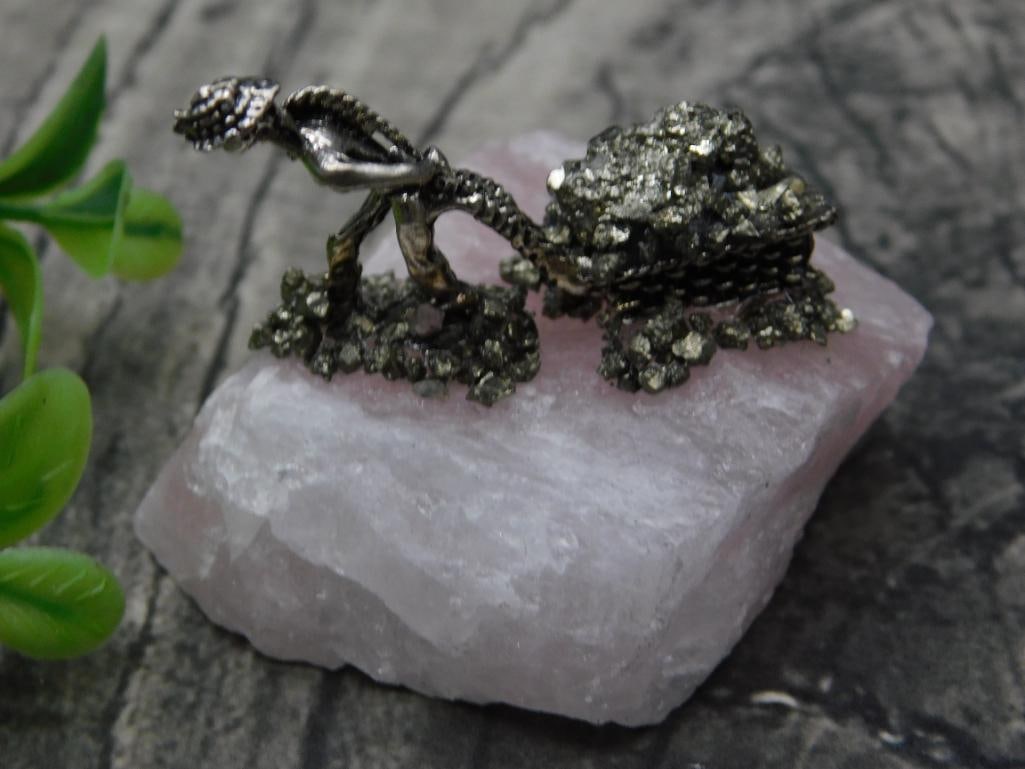 Pyrite Miner on Rose Quartz Base Rock Stone Lapidary Specimen: - Decorative collectible featuring pyrite on a pink quartz base. | - Centerpiece resembles a figure pulling a wheelbarrow with pyrite detailing. | - Mounted on pink quartz, adding color contrast and s