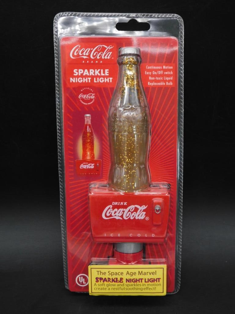 Coca-Cola Sparkle Night Light in Original Packaging: - Coca-Cola Sparkle Night Light with a design resembling a classic Coke bottle. | - Package includes the night light and original retro-themed backing card. | - Features glitter liquid inside the ligh