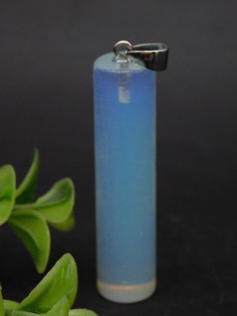 Cylindrical Opalite Pendant with Metal Bail: - Cylindrical opalite pendant with a translucent, iridescent appearance. | - Features a metal bail for attaching to a chain or cord. | - Measures approximately 15 grams in weight, as indicated on lot 