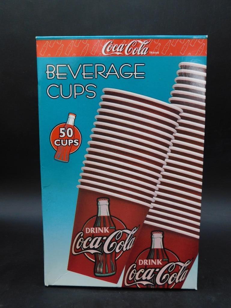 Coca-Cola Beverage Cups in Original Box (50 Count): - Coca-Cola branded disposable beverage cups in their original packaging. | - Includes 50 cups, each featuring the classic Coca-Cola logo. | - Box highlights key features such as insulation and durabl