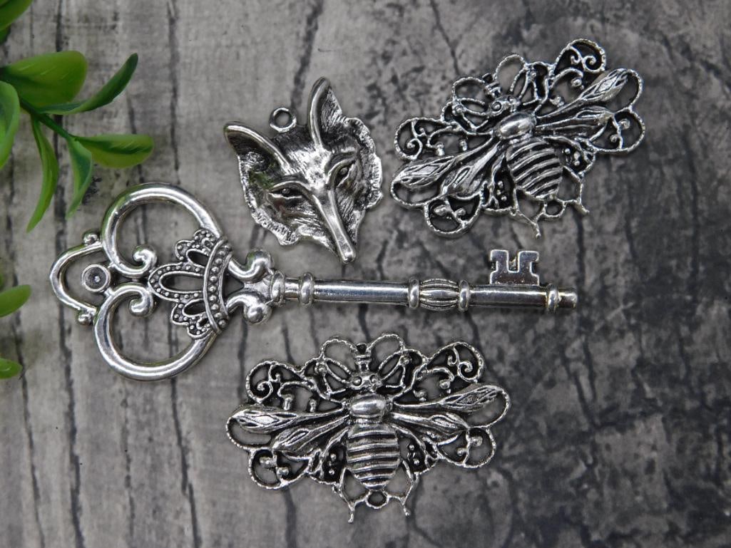 Silver-Tone Decorative Charms: - Includes four silver-tone charms: one ornate key, one fox head pendant, and two bee-shaped designs. | - Items showcase intricate detailing in their design. | - Key features an ornate crown motif at