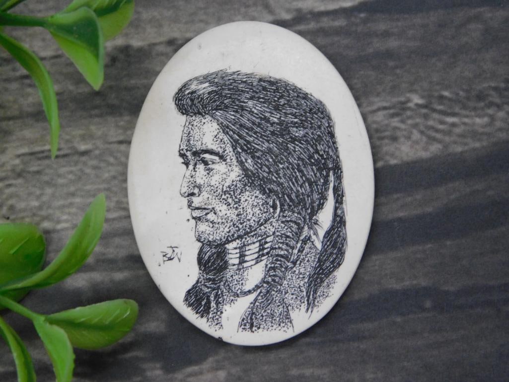 Scrimshaw Cabochon Rock Stone Lapidary Specimen: - Small oval-shaped stone with a detailed engraved portrait of a Native American figure in profile view. | - Black ink artwork showcasing intricate facial features and traditional attire. | - Accompan
