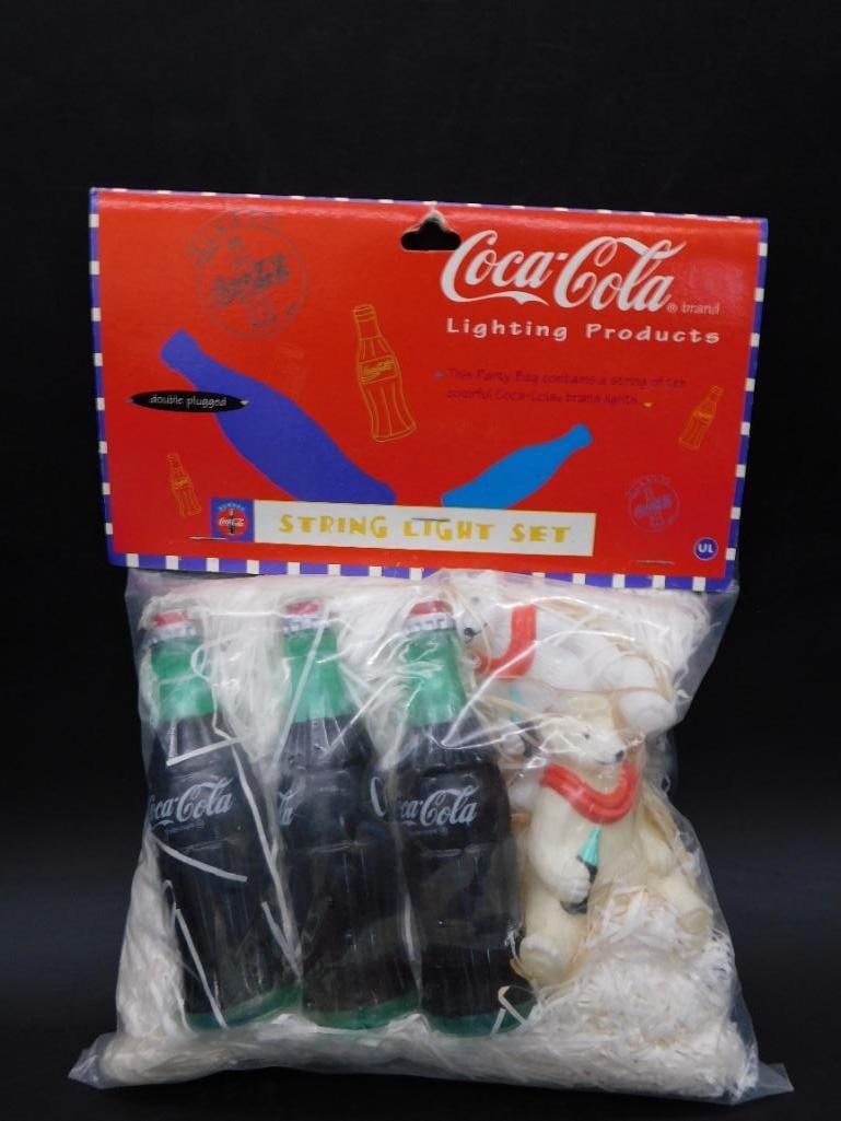 Coca-Cola Brand String Light Set in Original Packaging: - Vintage Coca-Cola brand string light set. | - Includes string of ten colorful Coca-Cola bottle-shaped lights. | - Packaged in original bag with header card displaying the Coca-Cola logo. | - Header