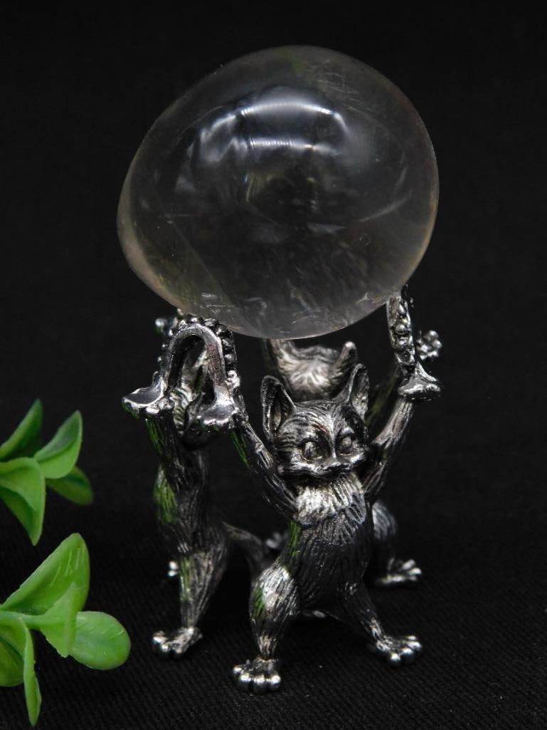 Silver Cat Figurine with Crystal Egg Rock Stone Lapidary Specimen: - Decorative silver-toned monkey figurine designed to hold a crystal sphere. | - The figurine is highly detailed and features multiple monkeys supporting the sphere. | - Includes a crystal-clear spher