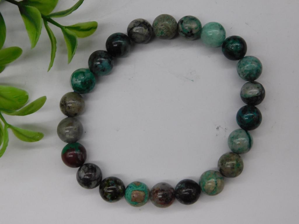 Stone Bead Stretch Bracelet Rock Stone Lapidary Specimen: - Polished round stone bead stretch bracelet with varying shades of green, black, and red hues. | - Beads appear uniform in size and shape. | - Bracelet designed with elastic stretch cord for an adjus