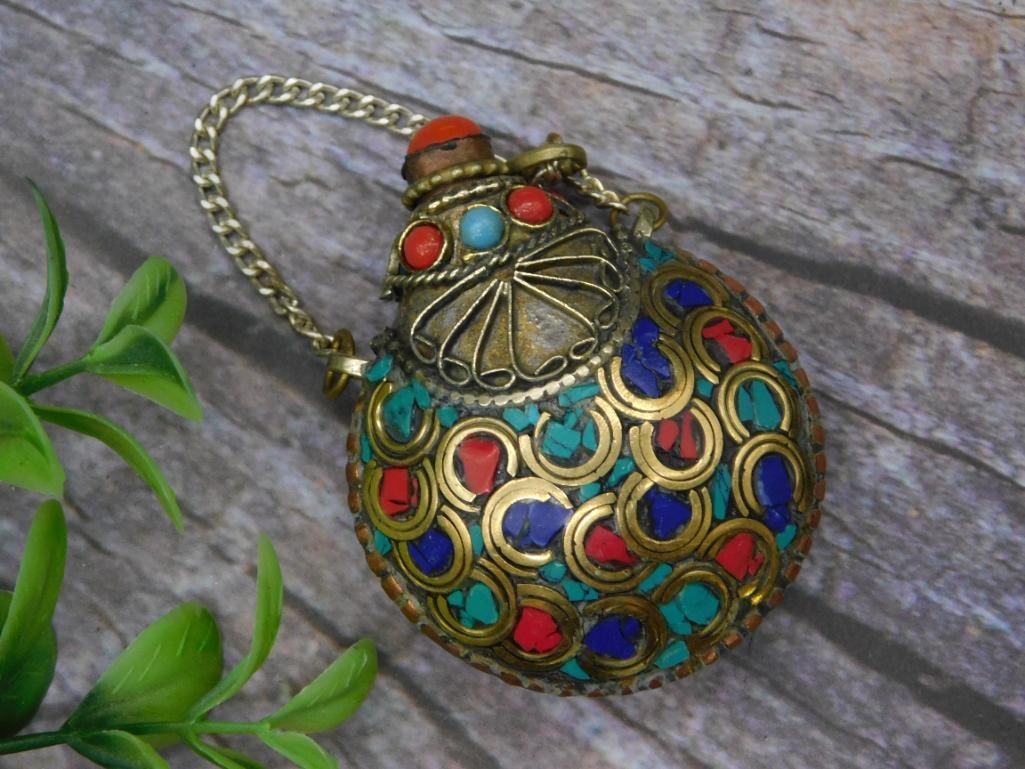 Snuff Bottle with Turquoise, Lapis Lazuli, and Red Coral: - Metal flask pendant featuring ornate multicolor inlays of red, turquoise, and blue stones. | - Includes decorative metal chain for hanging or carrying. | - Compact size as shown in comparison with a