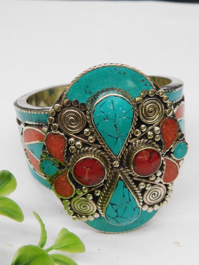 Turquoise and Coral Cuff Bracelet with Ornate Design: - Cuff bracelet featuring turquoise and coral inset stones. | - Intricate detailing with decorative spiral and geometric designs. | - Metal composition with a silver-tone finish. | - Hinged opening fo