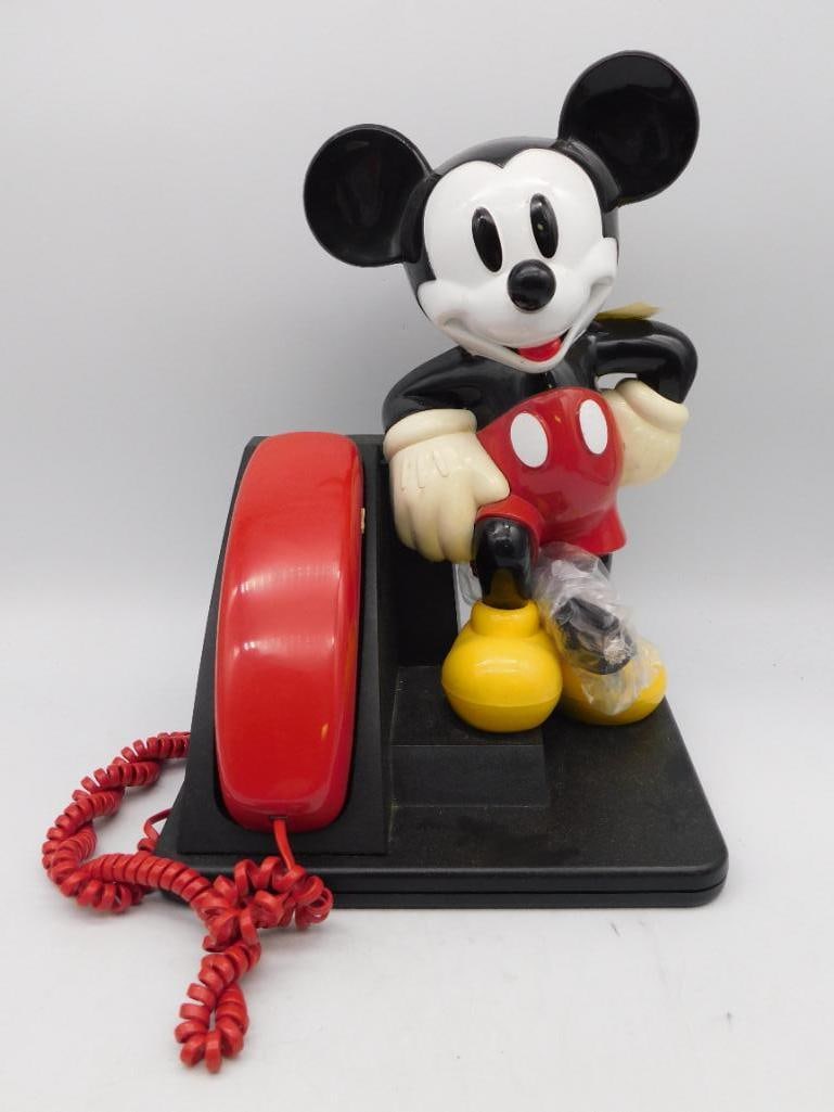 Mickey Mouse Novelty Landline Telephone with Handset: This Mickey Mouse-themed landline telephone features a colorful design with Mickey Mouse leaning on the phone base. The handset is red with a coiled cord and numeric keypad. The base includes visible 