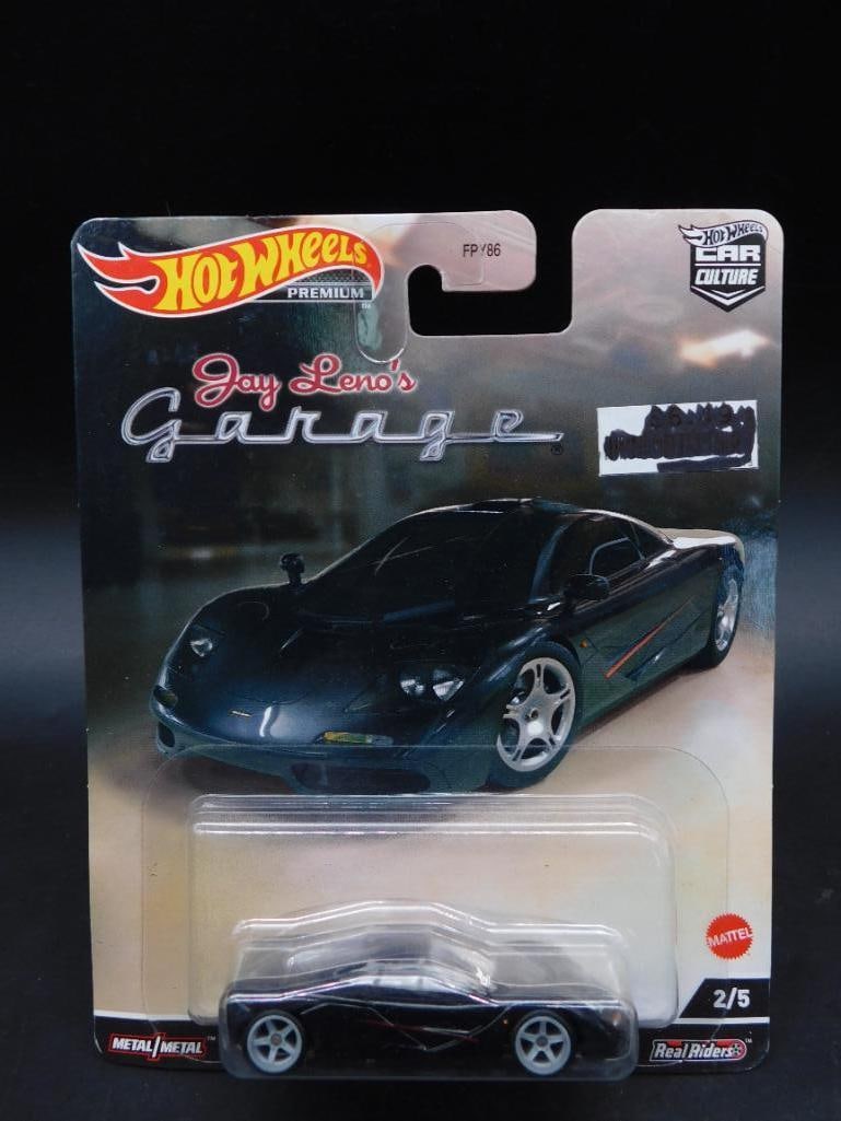 Hot Wheels Jay Lenos Garage 2/5 Die-Cast Car: Hot Wheels die-cast car from the 'Jay Leno's Garage' series. Features car number 2/5 in the collection. Packaging is intact and includes detailed artwork specific to the series. Back of the package pr