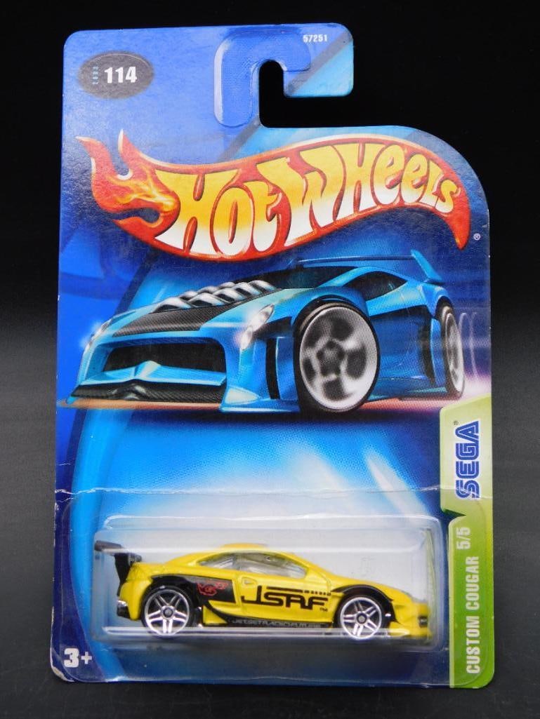 Hot Wheels Sega Custom Cougar #578 in Original Packaging: Hot Wheels Sega-themed die-cast car featuring the Custom Cougar (#578). Packaging shows minor wear but remains intact. Front of the packaging displays the car prominently with Sega branding, while the