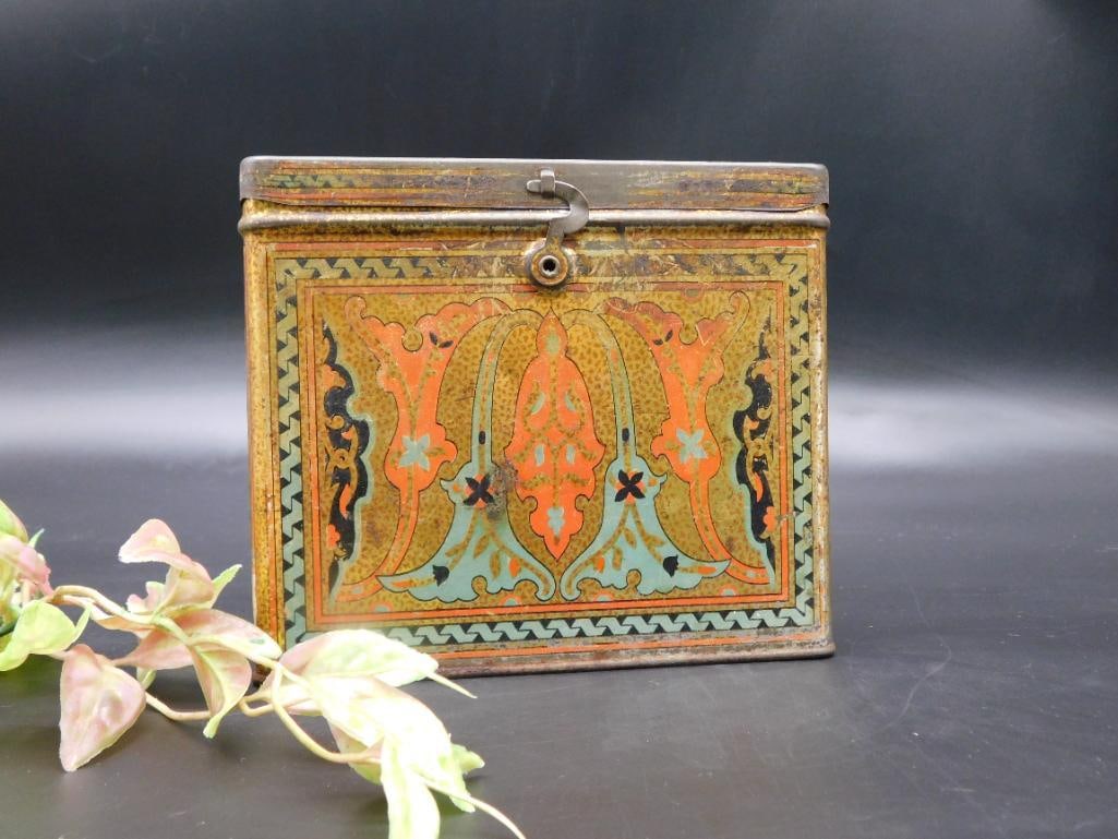 Decorated Uneeda Biscuit Tin Storage Container: Decorative Uneeda biscuit tin marked with the National Biscuit Company (NBC) logo. Features intricate painted patterns on all sides and a latch on the front. The lid has a handle for ease of use. This