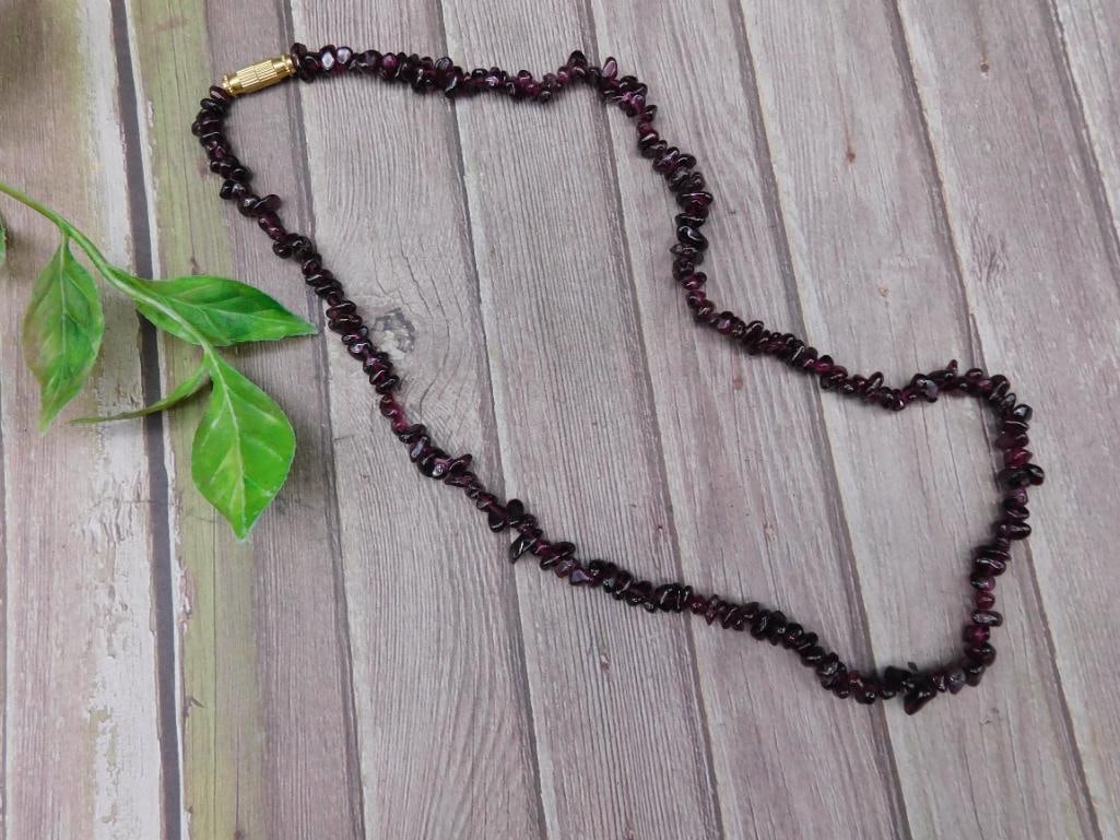Garnet Chip Bead Necklace with Barrel Clasp: This garnet chip bead necklace features polished natural garnet chips strung together in a continuous strand. It is secured with a gold-tone barrel clasp. Perfect for wear or use in crafting. The neck