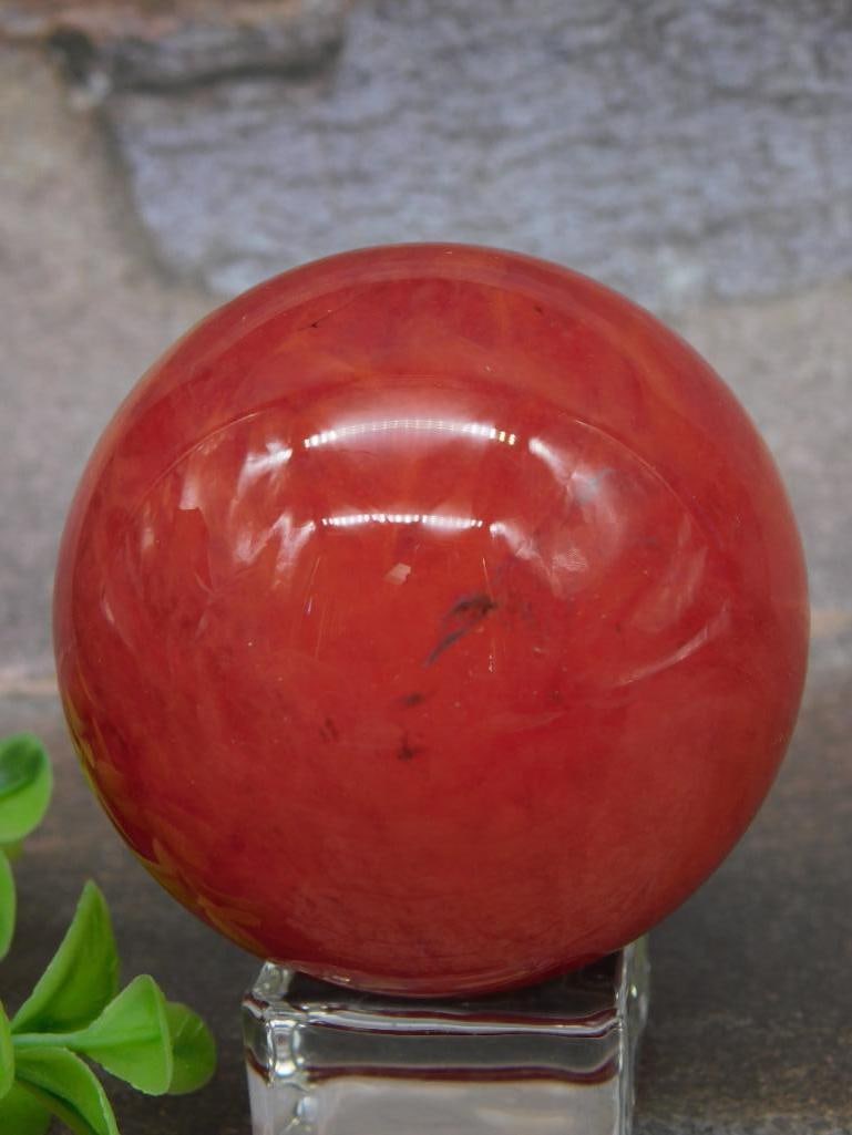 Polished QUARTZ ROCK STONE Red Sphere: A polished red sphere made of unknown material, weighing 184 grams. Includes a clear square acrylic display stand for presentation. The ruler and auction card in the image provide scale and identifica